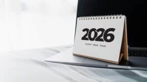 A desk calendar displaying the year 2026 beside a laptop